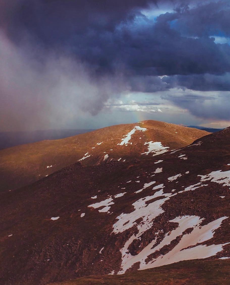 A snow-patched summit under storm clouds