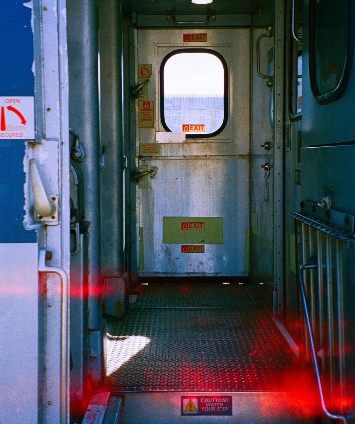 A train carriage vestibule with a red light leak